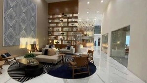 A modern living room with a sofa, chairs, a coffee table, and a bookshelf. - Condos CAM (Mazatlán)