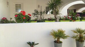 A white building with multiple arches and a balcony with potted plants and flowers. - Quiet house with beautiful sea and country views Colina Branca 10 (Carvoeiro)