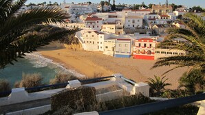 A coastal town with buildings along the beach, a clear sky, and palm trees. - Quiet house with beautiful sea and country views Colina Branca 10 (Carvoeiro)