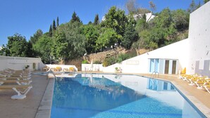 A swimming pool with lounge chairs and a stone wall in the background. - Quiet house with beautiful sea and country views Colina Branca 10 (Carvoeiro)