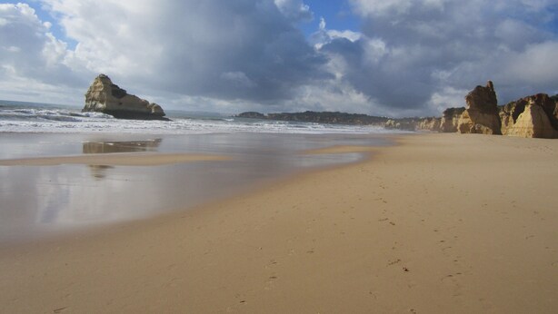 A beach with a sandy shore, large rock formations, and a cloudy sky. - Quiet house with beautiful sea and country views Colina Branca 10 (Carvoeiro)