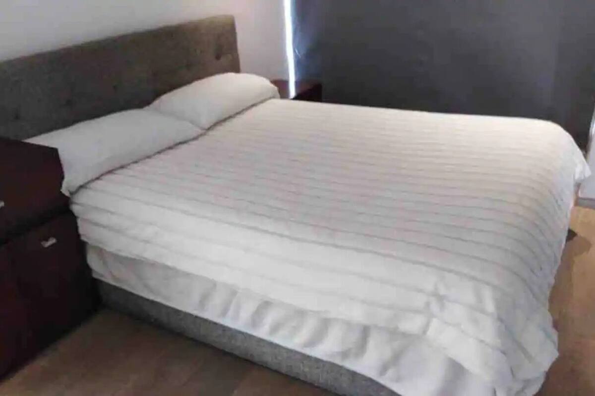 Un dormitorio con cama, una mesita de noche de madera y un aparador de color oscuro.
