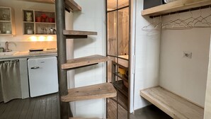 A compact kitchen with a built-in refrigerator, wooden shelves, and a hanging rack. - A cottage in the middle of the countryside just a stone's throw from the center of Florence<br> (Toscana)