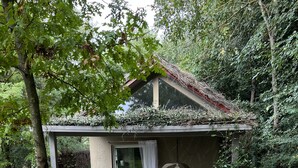 A small, rustic cabin with a stone patio, a table with chairs, and a hanging light fixture. - A cottage in the middle of the countryside just a stone's throw from the center of Florence<br> (Toscana)
