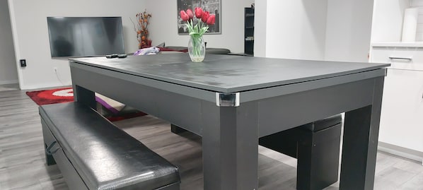 Un comedor moderno con una mesa rectangular, un banco y un jarrón de tulipanes rojos.