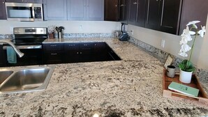 A modern kitchen with dark cabinets, a granite countertop, stainless steel appliances, and a small potted orchid. - Beautiful brand new house with breathtaking Shining Mountain views. (Ennis)