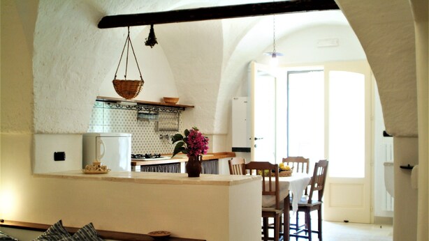 Una cocina acogedora con comedor, que incluye una isla central, cestas colgantes y vistas al comedor contiguo.