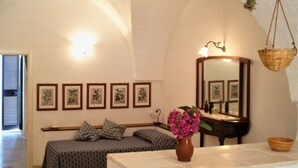 Una habitación acogedora con una cama, un espejo, impresiones botánicas enmarcadas y un florero con flores.