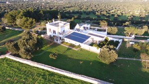 Vista aérea de una extensa propiedad con un edificio principal, varias construcciones secundarias y amplios jardines ajardinados.