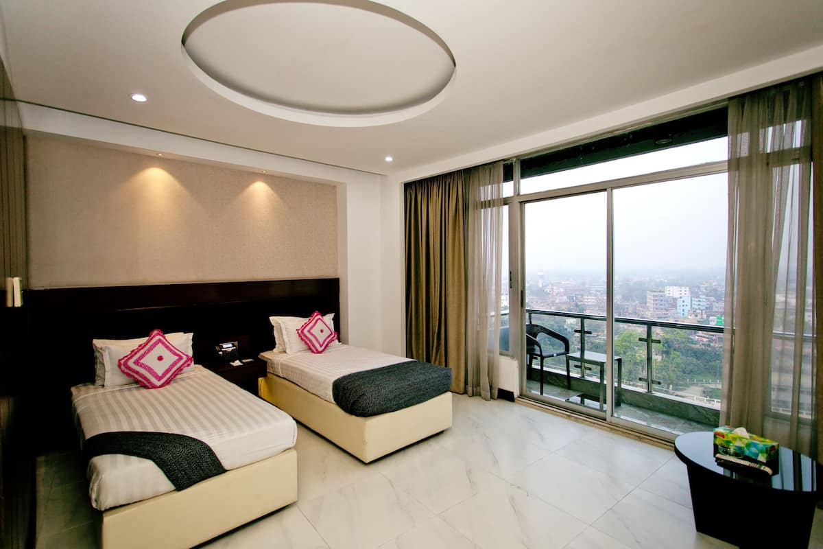 A hotel room with two beds, a balcony, and a city view.