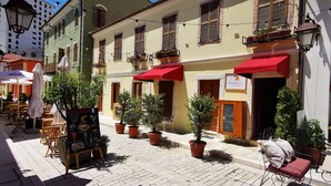 A cobblestone street with outdoor seating, potted plants, and a building with red awnings. - Bohemian Boutique Suites (Vlorë)