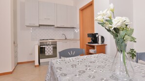 Una cocina moderna con armarios blancos, una mesa de comedor con mantel estampado y un florero con flores blancas.