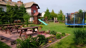 Un parc équipé de tables de pique-nique, d’une aire de jeux et d’un trampoline.