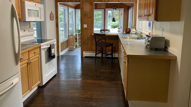 Una cocina con armarios de madera, un microondas, un tostador y un lavabo.
