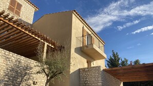 Un edificio con fachada de piedra, balcón de madera y cielo azul despejado.