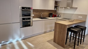 Una cocina moderna con electrodomésticos integrados, una isla de madera y taburetes de bar.