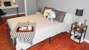 Une chambre bien rangée, avec un lit, une table de chevet et un espace bureau.