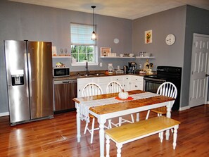 Enjoy cooking in this well-equipped kitchen with modern appliances, a dining table, and a window overlooking lush greenery.