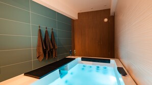 Ein modernes Badezimmer mit einer großen Badewanne, einer Wand aus Holzpaneelen und einem Handtuchhalter mit Handtüchern.