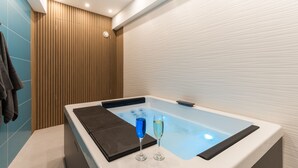 Ein modernes Badezimmer mit einer großen Badewanne, einem Handtuchhalter und einem Glas blauer Flüssigkeit.
