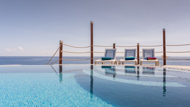 Ein Infinity-Pool mit Liegestühlen und Blick auf den Ozean.