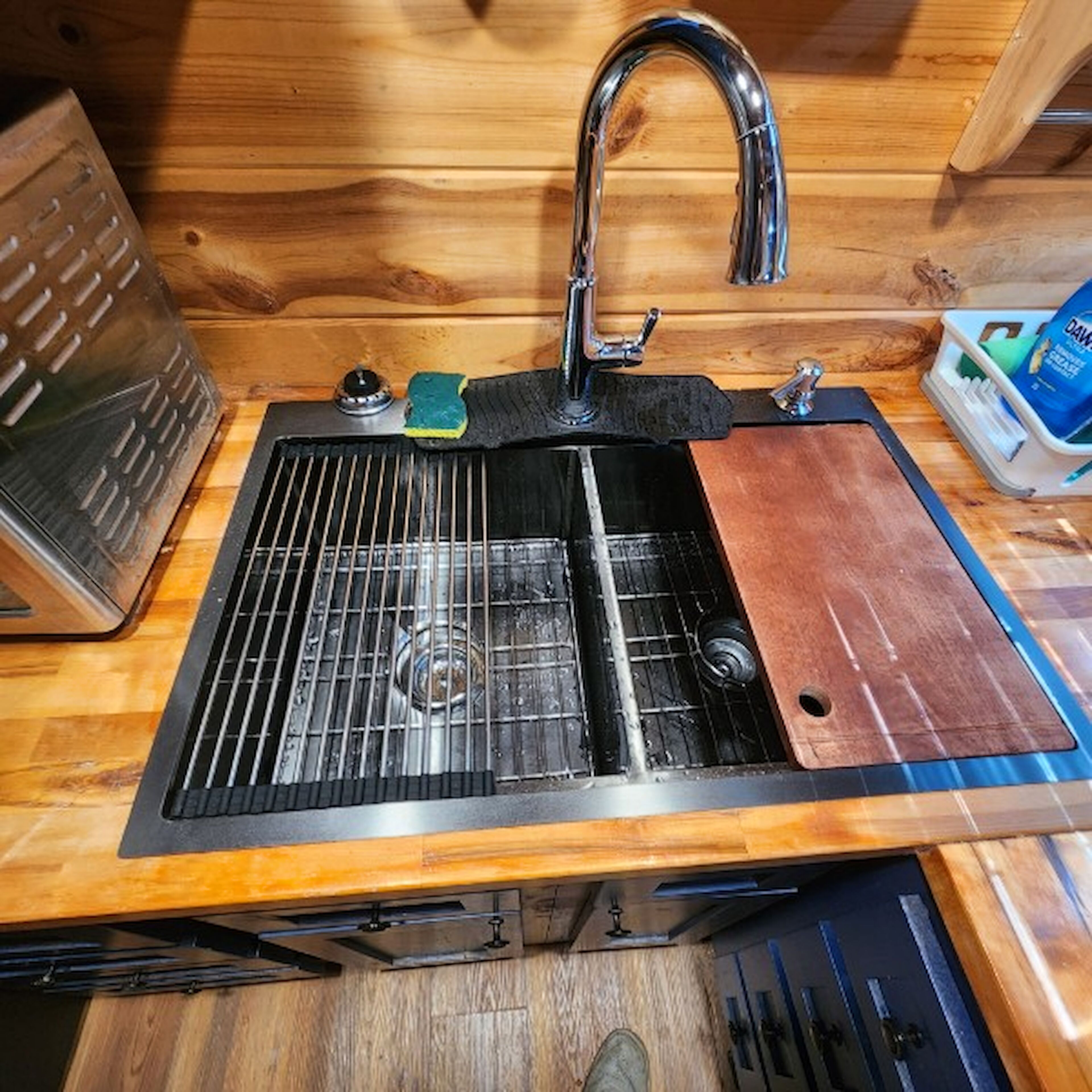 A kitchen with a stainless steel sink, a cutting board, and a dish soap dispenser.