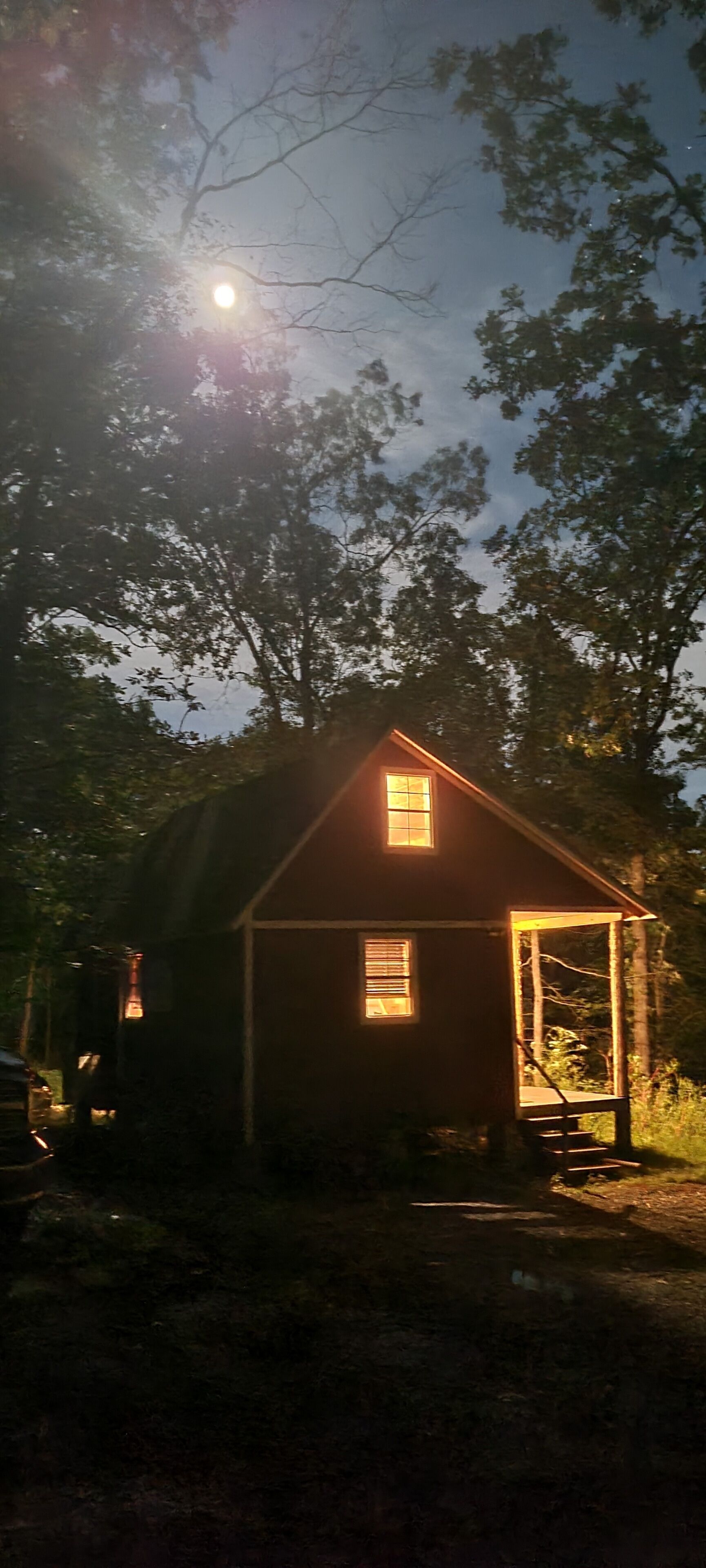 A small wooden cabin with a single window and a door, surrounded by trees.