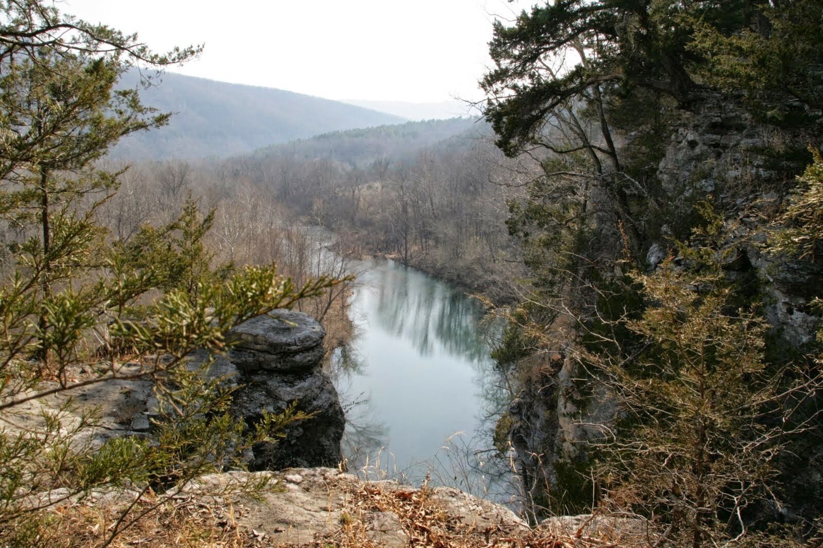 Una valle fluviale con terreno roccioso e vegetazione rada.