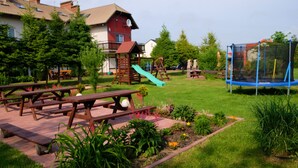 Een park met picknicktafels, een speeltuin en een trampoline.