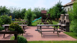 Een speeltuin met glijbanen en klimconstructies, picknicktafels en banken.