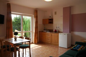 Une cuisine compacte avec des meubles en bois, un réfrigérateur blanc et un coin repas comprenant une table et des chaises.