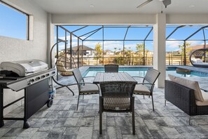Enjoy al fresco dining and socializing in this inviting patio area with a grill station, comfortable seating, and a pool view.