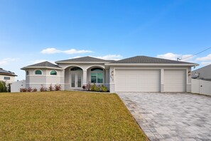 Stunning two-story home with a central entrance, arched windows, and a garage door.
