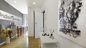 A hallway with a white table, a vase with flowers, and a large black and white cityscape painting on the wall. - Vivaldo Suite - Piazza dei Martiri (Naples)