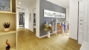 A modern interior with a wooden floor, a grey accent wall, a white door, and a dining area with stools. - Vivaldo Suite - Piazza dei Martiri (Naples)