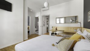 A modern hotel room with a large bed, a desk, a chair, a mirror, and a television. - Vivaldo Suite - Piazza dei Martiri (Naples)