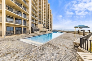 A hotel with a pool area, multiple balconies, and a view of the ocean.