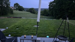 Una veranda esterna con tavolo, sedie e una lampada a sospensione.