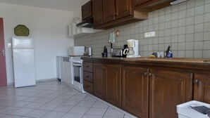 Keittiössä on puukuvioiset kaapit, valkoinen jääkaappi, astianpesukone ja laatoitettu välitila.