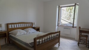 Makuuhuoneessa on puinen sänky, kaksi yöpöytää, tuoli ja ikkuna, josta avautuu näkymä vehreään maisemaan.