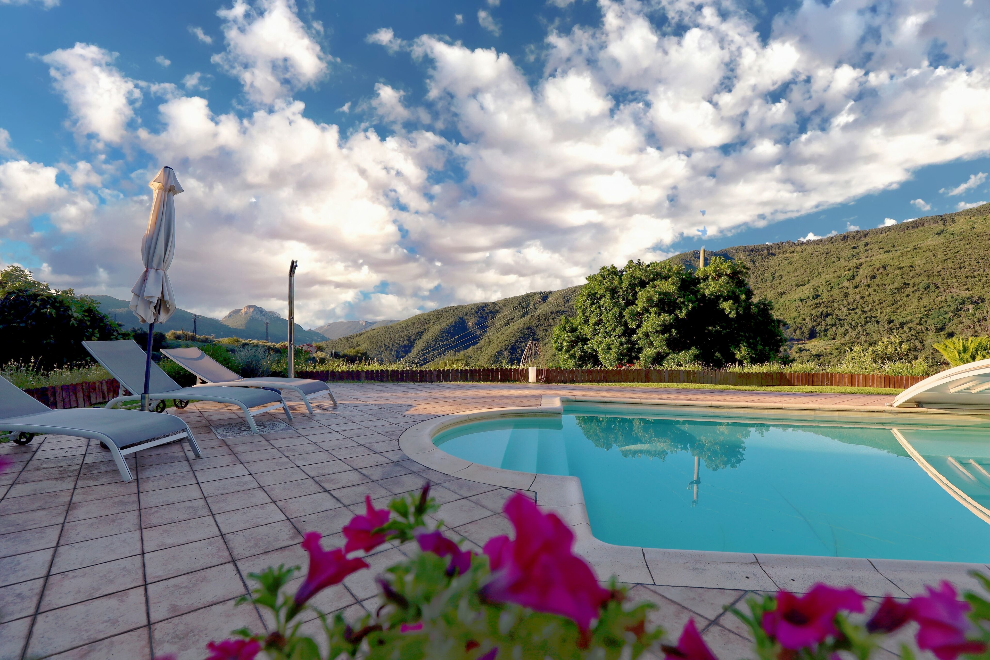 A pool area with lounge chairs and a view of a mountainous landscape.