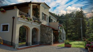 Una casa de dos pisos con fachada de piedra, ventanas arqueadas y un balcón con jardineras.