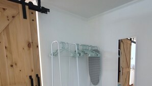 A room with a wooden door, a metal rack with storage bins, and a mirror on the wall.