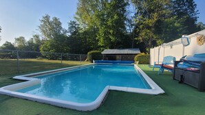 A rectangular swimming pool with a white edge, surrounded by a green artificial turf.