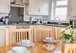 A modern kitchen with granite countertops, stainless steel appliances, and wooden chairs.