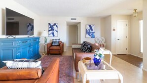 A living room with a blue cabinet, a brown sofa, a white coffee table, and a television. - Spacious Vacation Home Sun City West 55 Community (Sun City West)