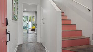Eine Treppe mit Holzdielen und Geländer, die zu einem offenen Bereich mit einer Glastür führt.