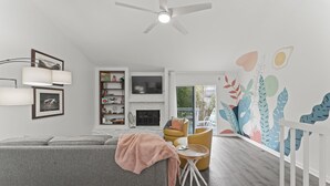 Ein modernes Wohnzimmer mit einer grauen Couch, einem kleinen runden Tisch und einer weißen Geländer.