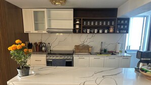 Una cucina moderna con isola in marmo, sedie in legno, piano cottura e macchina per caffè.