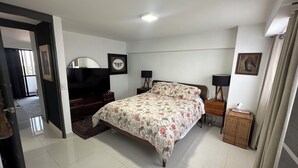 Una camera da letto con un letto, una TV, una cassettiera e uno specchio.